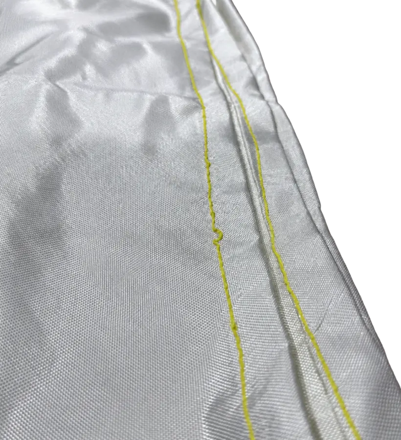 Close-up of white woven fire blanket fabric with yellow stitching along the folded edge